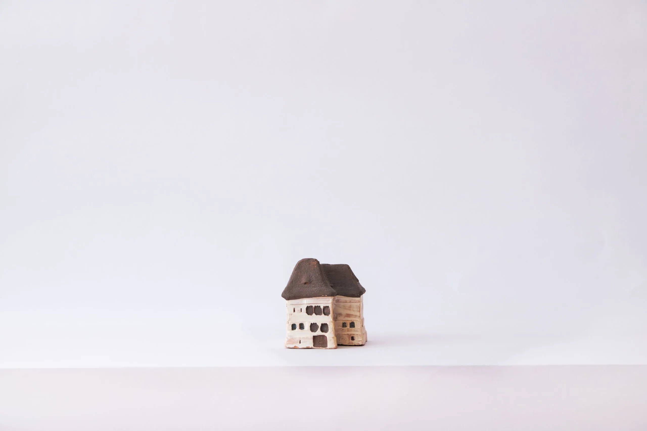 A small clay model house standing alone on a plain white background